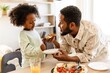 © Drobot Dean - Father holding a slice of pizza and a plate while smiling and talking to his daughter while they stand at the table