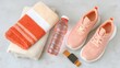 © Maryna - Bottle of water, a towel, and a pair of pink sneakers are on a table. Concept of preparation for a workout or a day at the gym