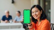 © aima - Woman holding green screen mobile phone