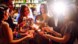 © maxbelchenko - Young friends having fun with sparklers and glasses of champagne at corporate party. Handsome men and woman spend time together, celebrating New Year in cozy space. Сoncept is festive and fun.