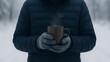© Anna - Person holding hot drink outdoors in winter with steaming mug and warm gloves in snowy cold environment