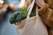 © lashkhidzetim - A woman is holding a bag of vegetables, including broccoli and spinach