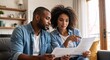 © Vasiliy - African American couple reviewing financial documents at home. Young man and woman sitting on sofa reading a contract or budget plan together