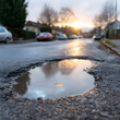 © MonkeyZ - Pothole Reflection at Sunset An Urban Scene on a Wet Road with a Leaf