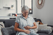 © Daniel - Elderly woman sits on a sofa at home holding her stomach, experiencing abdominal pain and discomfort. She looks tired and stressed while managing digestive issues during her daily life.