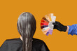 © Pixel-Shot - Female hairdresser's hand with color palette dyeing hair of woman on orange background, back view