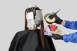 © Pixel-Shot - Female hairdresser's hands with color palette dyeing hair of client on light background, back view