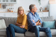 © Prostock-studio - A man and woman are sitting on opposite ends of a sofa, showing signs of disagreement. They have crossed arms and look away from each other in a contemporary living room.