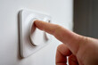 © Lazy_Bear - Close-up of hand pressing modern white wall light switch on interior wall to turn on indoor lighting. Concept of electricity use, home control and energy consumption