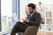 © sofiko14 - An Arabian businessman gestures while participating in a video conference on his laptop