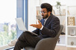 © sofiko14 - An Indian businessman gestures while participating in a video conference on his laptop