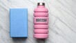 © NoorArt Studio - Pink water bottle and blue gym towel on marble surface