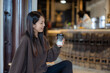 © leungchopan - Woman looking at coffee cup inside cafe