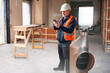 © Grispb - Building renovation supervisor checks project updates on a smartphone, overseeing interior reconstruction work and coordinating tasks on the construction site.
