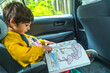 © unai - Toddler coloring in car seat during road trip on vancouver island