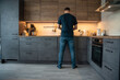 © dtatiana - Man cooking in the kitchen while facing the stove. Home meal preparation.