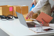 © Natee Meepian - E-commerce Team Managing Packages and Laptop in Modern Office