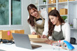 © Natee Meepian - Women in E-commerce Office Collaborating on Laptop and Packages