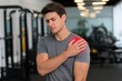 © Regina Gafarova - Young man experiencing shoulder pain while exercising in a gym, showcasing discomfort and the importance of proper physical care during workouts