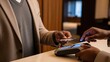 © Tanakorn - African American man completes a hotel payment using a credit card on a sleek, glowing terminal at the elegant front desk, showcasing modern digital convenience