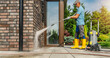 © Tomasz Zajda - Man Uses Pressure Washer on Brick Wall During Sunny Day