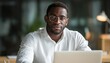 © Tetiana - African American Man In White Shirt Working On Laptop In Modern Office, Dark Skinned With Glasses. Horizontal Blurred Image.