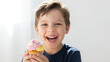 © Polina - Joyful boy beaming with laughter while holding a decorated cupcake