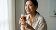 © Image stock - Joyful young asian woman enjoying a refreshing iced coffee by the window
