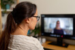 © gunzexx png and bg - A woman with glasses intensely focused on a video conference from her home office, representing modern work culture and the shift towards remote communication.