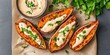 © Hryhor Denys - Halved baked sweet potatoes with creamy plant based sauce and fresh parsley. Delicious healthy vegan food arranged on brown paper, with a side bowl.