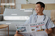 © Pixel-Shot - Young Asian man reading newspaper at home