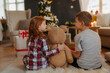 © Halfpoint - Rear view of siblings opening christmas presents in pajamas.