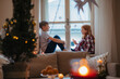 © Halfpoint - Small girl and boy sitting on window sill in pajamas. Christmas time.