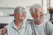 © Daniel - Happy senior couple relaxing together at home on sofa, elderly retired woman and partner looking out the window while sharing a calm moment, enjoying peaceful domestic life and emotional connection