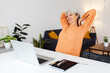 © Xavier Lorenzo - Senior woman stretching while working remotely on laptop sitting at desk in the living room, taking a break from work