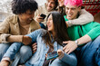 © Xavier Lorenzo - Young group of people having fun while hanging out and using mobile phones sitting together outdoor