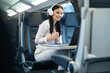 © Dejan - A smiling woman is participating in an online meeting on a laptop while sitting on a train, illustrating the blend of travel and technology in the modern workspace.