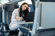 © Dejan - A woman appears deep in thought while working on her laptop in a train, illustrating a modern lifestyle of mobility and productivity in transit.