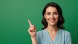 © Bale - Bright smiling woman in casual attire pointing upwards against vibrant green background for