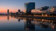 © kirania - Modern waterfront cityscape reflects in calm water during twilight hours