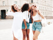 © halayalex - Three young beautiful smiling hipster female in trendy summer clothes.Sexy carefree multiracial women posing on the street background.Positive models having fun. Turn around and looking at camera