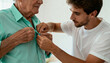 © Anna - Young man helping an elderly senior father get dressed. Caregiver assisting with buttoning a shirt. Family support and homecare concept