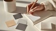 © fotofabrika - Writing notes with pencil on a notepad beside colorful paper squares in a well-lit space