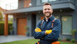 © Pete - Smiling male technician in work clothes stands outside modern house. He has safety gloves and tools, ready for electrical or network installation. Professional service man with beard. He looks happy.