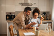 © Jelena - Couple Shopping Online At Kitchen Table With Laptop And Credit Card