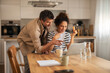 © Jelena - Couple in Modern Kitchen Using Laptop and Credit Card for Online Shopping
