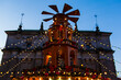 © pijav4uk - A festive structure stands decorated with lights and ornaments. The scene shows a lively market at dusk with the holiday spirit. Christmas market in Gdansk, Poland