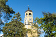 © Travel 'n' Lifestyle - View of Amiralitetsklockstapeln clock tower standing tall from below, framed by vibrant green foliage under blue sky, Karlskrona, Blekinge County, Sweden.