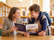 © Aurora Aesthetics - Career counselor showing brochure to male student close up future planning guidance university choice education concept smiling mentor teenager discussion happy advice high school library background
