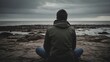 © Вячеслав Краснов - Person sits on rocky shore looking at ocean during Christmas season under cloudy skies Generative AI